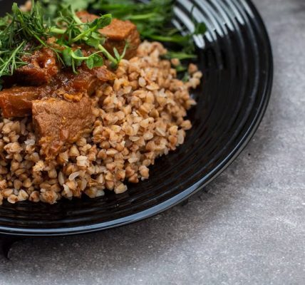 Delicious buckwheat with seasoned beef and greens served on a black plate.