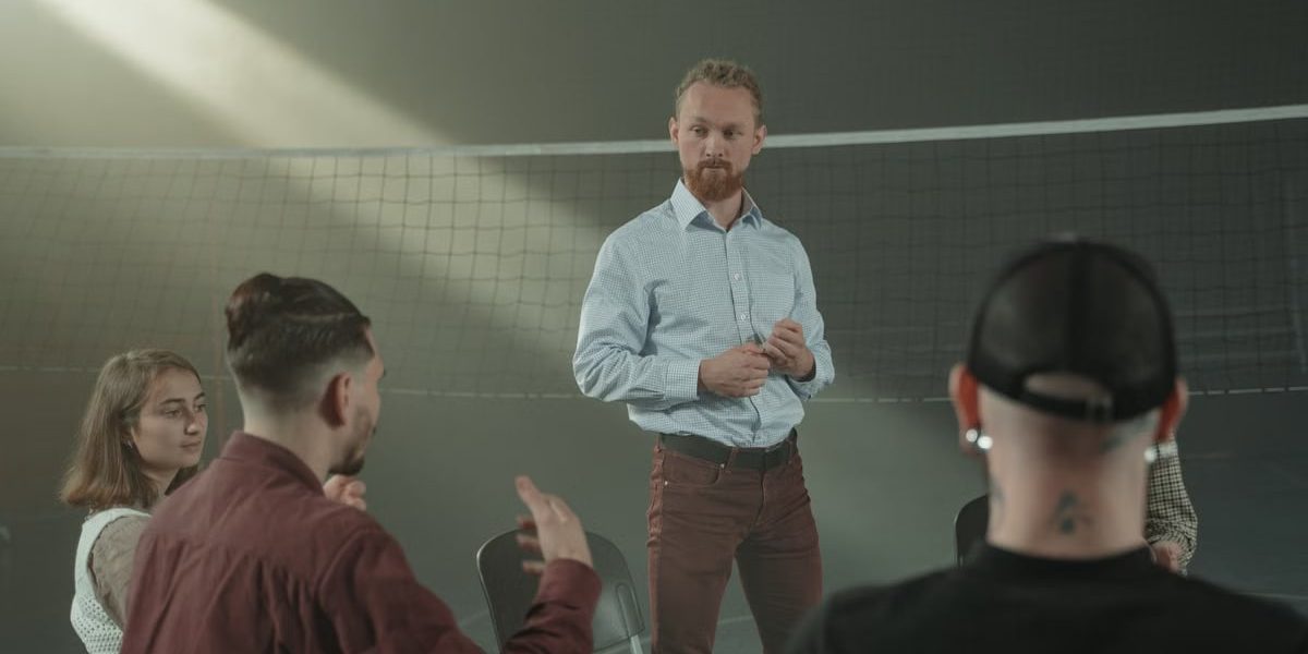 Four people engaged in a group discussion inside a room with a net background.