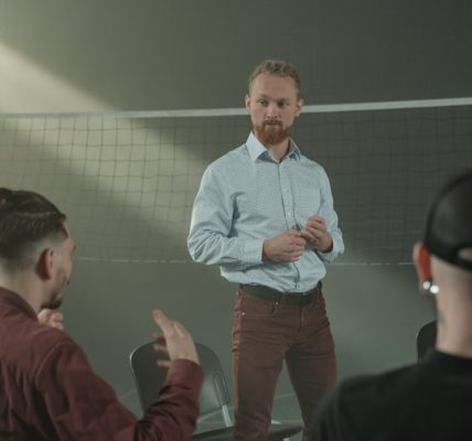 Four people engaged in a group discussion inside a room with a net background.